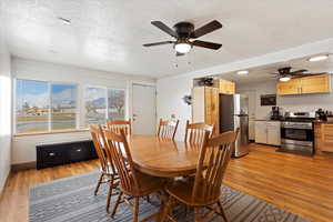 Dining area with ceiling fan, a textured ceiling, and light wood-type flooring