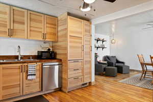 Kitchen featuring sink, stainless steel dishwasher, ceiling fan, light hardwood / wood-style floors, and light brown cabinets