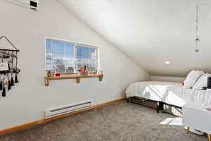 Carpeted bedroom with vaulted ceiling, a textured ceiling, and baseboard heating