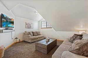 Living room with carpet, lofted ceiling, a textured ceiling, and baseboard heating