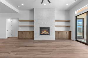 Unfurnished living room with light hardwood / wood-style floors, a tile fireplace, and ceiling fan