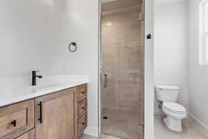 Bathroom with tile patterned floors, vanity, toilet, and a shower with door