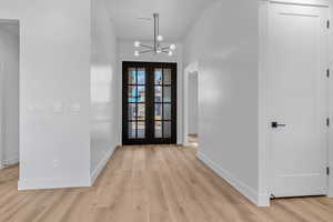 Entryway with french doors, a chandelier, and light hardwood / wood-style flooring