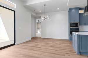 Kitchen with built in microwave, blue cabinets, light hardwood / wood-style flooring, oven, and backsplash