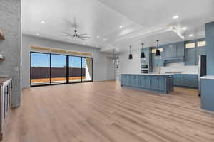 Kitchen featuring stainless steel refrigerator, built in microwave, hanging light fixtures, ceiling fan, and light wood-type flooring