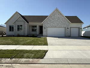 View of front of property with a garage, driveway, a front lawn, and stone siding