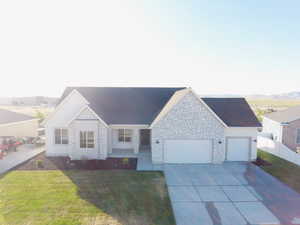 Single story home featuring an attached garage, driveway, and stone siding