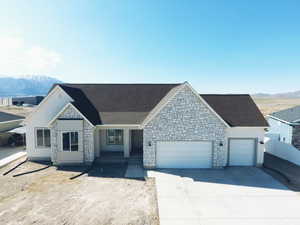 View of front of property featuring an attached garage, driveway, a shingled roof, and a mountain view