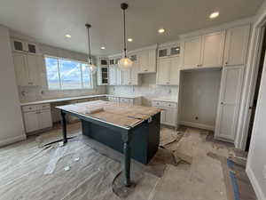 Kitchen with a kitchen island, recessed lighting, glass insert cabinets, and tasteful backsplash