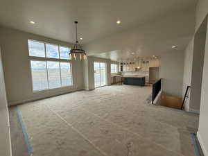 Unfurnished living room featuring an inviting chandelier, baseboards, and recessed lighting