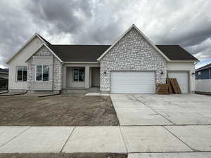 Single story home with stucco siding, driveway, stone siding, and a garage