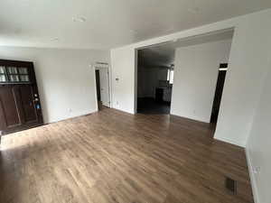 Unfurnished living room featuring dark wood-type flooring