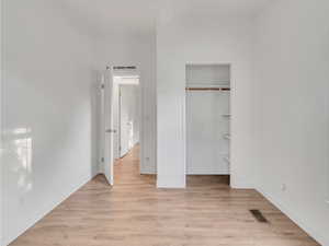 Unfurnished bedroom with light hardwood / wood-style floors and a closet