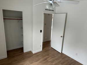 Unfurnished bedroom with dark wood-type flooring, a closet, and ceiling fan