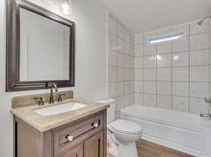 Full bathroom with tiled shower / bath combo, vanity, hardwood / wood-style floors, and toilet