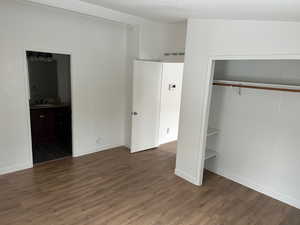 Unfurnished bedroom featuring sink, ensuite bath, a textured ceiling, dark hardwood / wood-style flooring, and a closet