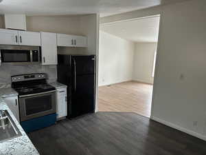 Kitchen featuring stainless steel appliances, white cabinets, dark hardwood / wood-style flooring, and decorative backsplash