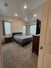 Carpeted bedroom with multiple windows, lofted ceiling, and a textured ceiling