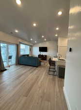 Living room featuring vaulted ceiling, sink, and light wood-type flooring