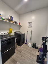 Clothes washing area featuring baseboards, light wood-style floors, laundry area, and washing machine and clothes dryer