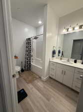 Full bathroom featuring vanity, hardwood / wood-style floors, shower / bath combination with curtain, and toilet