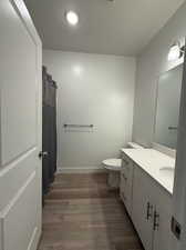 Bathroom featuring hardwood / wood-style floors, vanity, a textured ceiling, curtained shower, and toilet