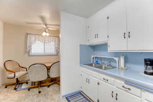 Kitchen with sink, ceiling fan, backsplash, a textured ceiling, and white cabinets