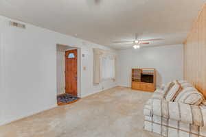 Unfurnished living room with ceiling fan, light carpet, and a textured ceiling