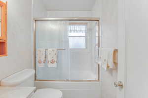 Full bathroom featuring vanity, shower / bath combination with glass door, and toilet