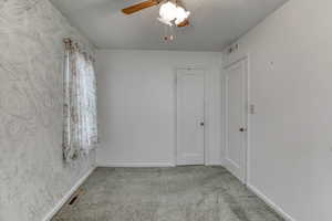 Unfurnished room with ceiling fan, light colored carpet, and a textured ceiling
