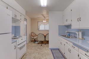 Kitchen featuring white cabinetry, sink, ceiling fan, and white appliances