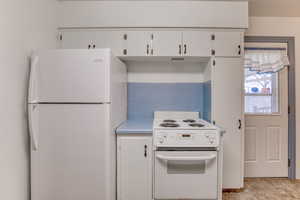 Kitchen featuring white cabinetry and white appliances