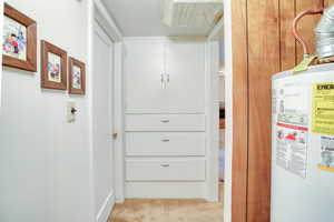 Hall with water heater, light carpet, and a textured ceiling