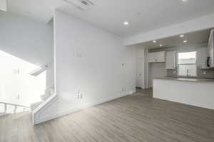 Unfurnished living room featuring hardwood / wood-style flooring and sink