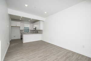 Unfurnished living room featuring sink and light wood-type flooring