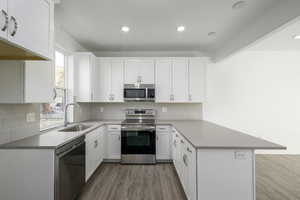 Kitchen featuring sink, white cabinets, kitchen peninsula, stainless steel appliances, and light hardwood / wood-style flooring