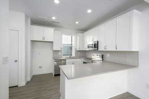 Kitchen with white cabinetry, appliances with stainless steel finishes, kitchen peninsula, and sink