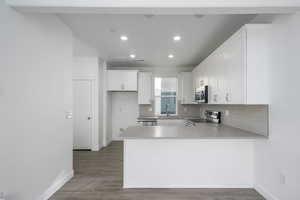 Kitchen with white cabinetry, appliances with stainless steel finishes, kitchen peninsula, and sink