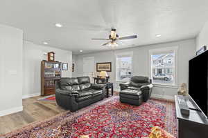 Living room featuring ceiling fan, light hardwood / wood-style floors, and a textured ceiling