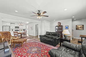 Living room with ceiling fan with notable chandelier and light hardwood / wood-style floors