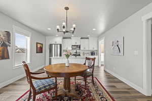 Dining space with sink, wood-type flooring, and a chandelier