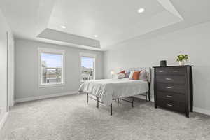 Carpeted bedroom featuring a tray ceiling