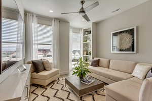 Living room featuring built in shelves, light hardwood / wood-style floors, and ceiling fan