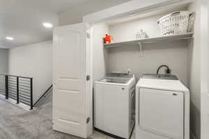 Laundry room featuring washing machine and clothes dryer and light colored carpet