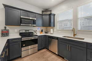 Kitchen with appliances with stainless steel finishes, sink, and light hardwood / wood-style floors