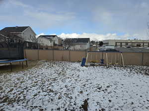 Yard layered in snow with a trampoline