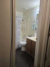 Full bathroom featuring toilet, a textured ceiling, vanity, shower / bath combination with curtain, and hardwood / wood-style floors