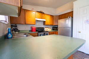 Kitchen with sink, vaulted ceiling, and appliances with stainless steel finishes