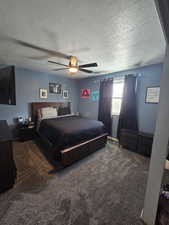 Carpeted bedroom with ceiling fan and a textured ceiling