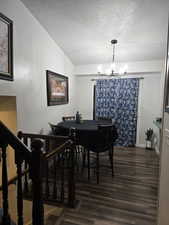 Dining space featuring lofted ceiling, a textured ceiling, a notable chandelier, and dark hardwood / wood-style flooring